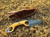 leather sheath and Damascus knife side by side laid on grass in natural lightning