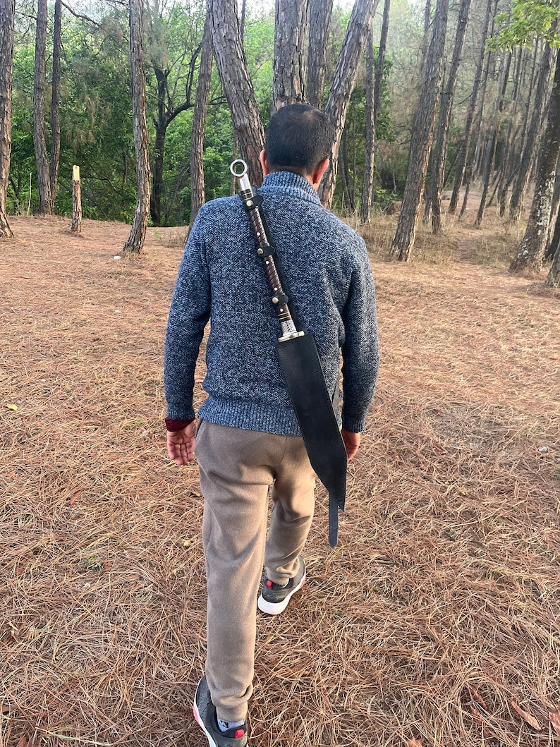 Person walking in a forest carrying a rifle on their back