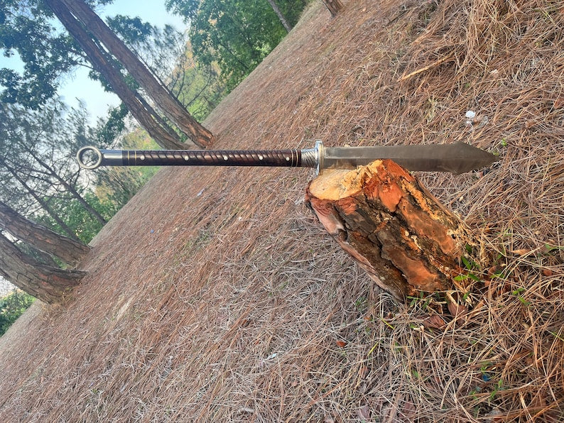 Sword on a log with a natural background of trees and grass