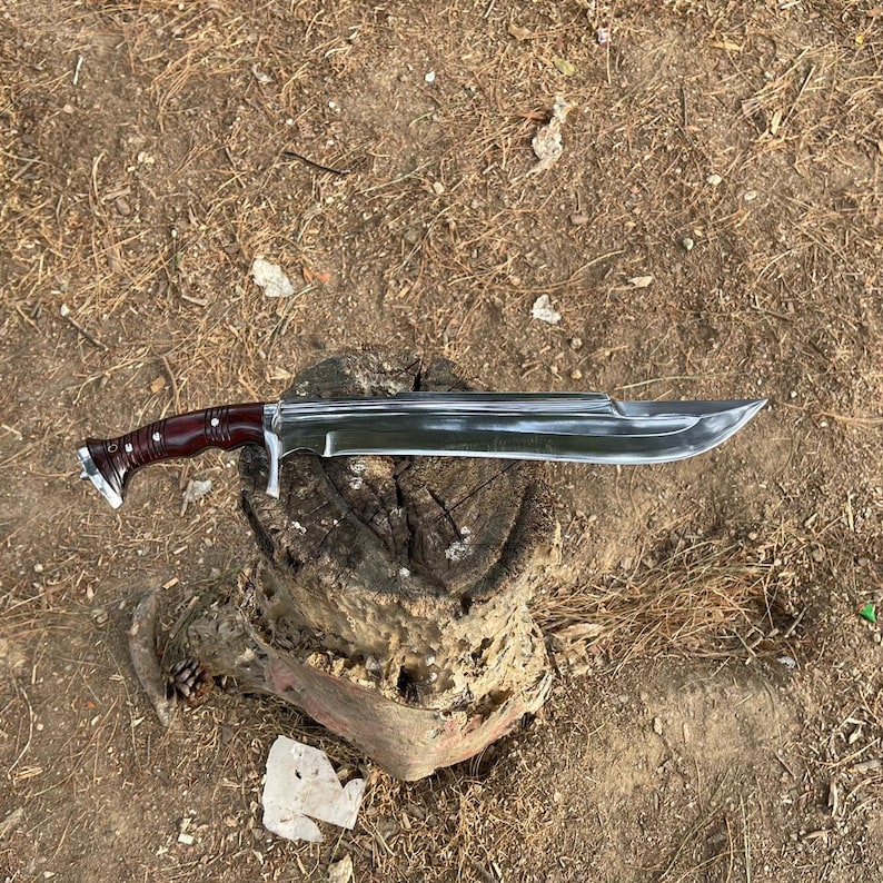 Sword with a wooden handle on a dirt ground used in forest for camping and protection