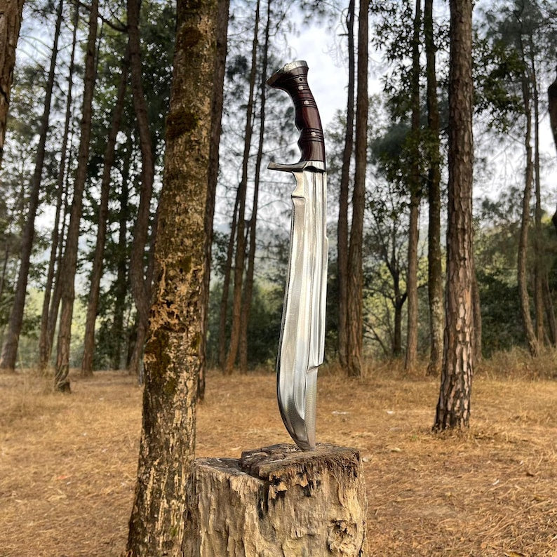 Shining blade knife on a wooden stump in a forest for camping and protection