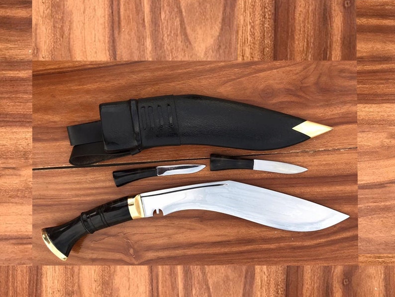 Two kukri knives with sheaths on a wooden surface