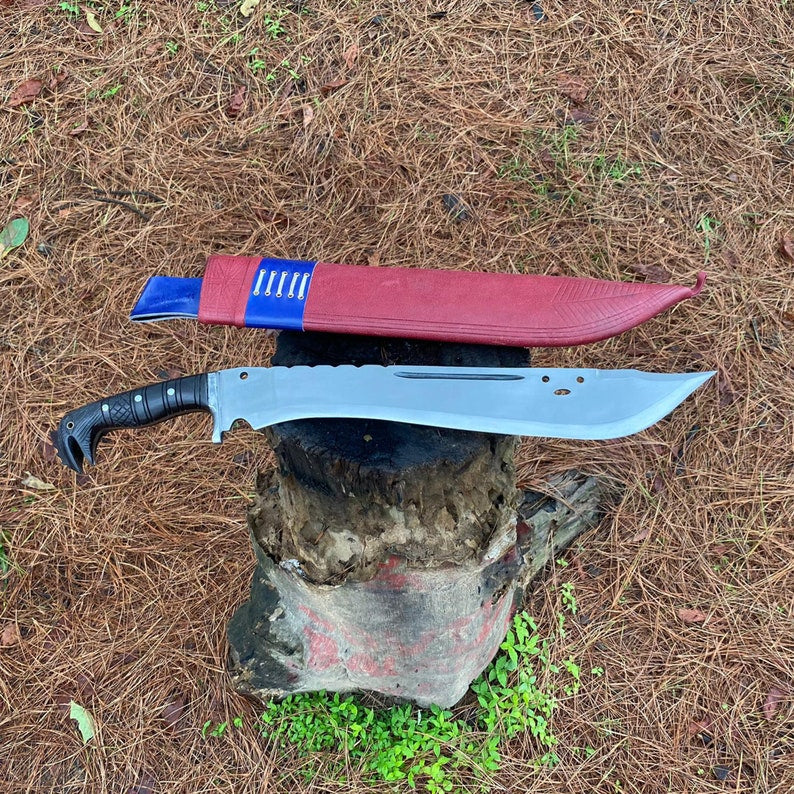 Large machete knife with a red leather sheath on a rock in a forest  for camping and protection