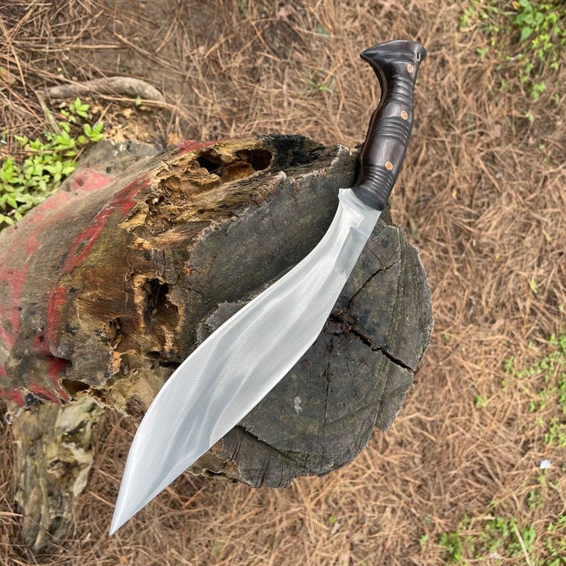 Decorative knife with a black handle on a wooden stump outdoors