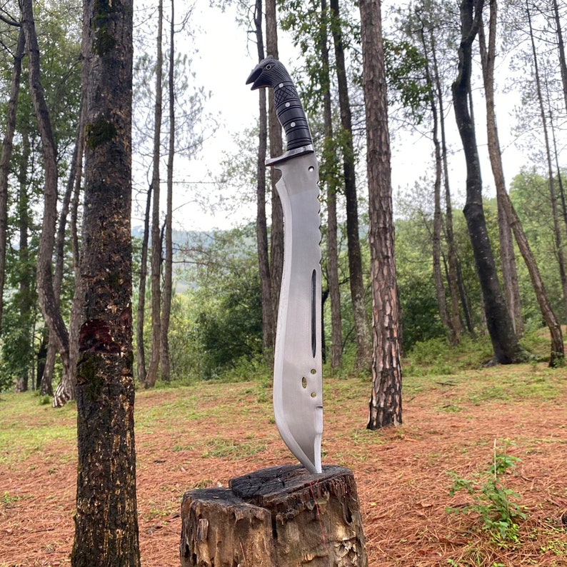 Large machete knife with a black handle on a wooden stump in a forest for camping and protection