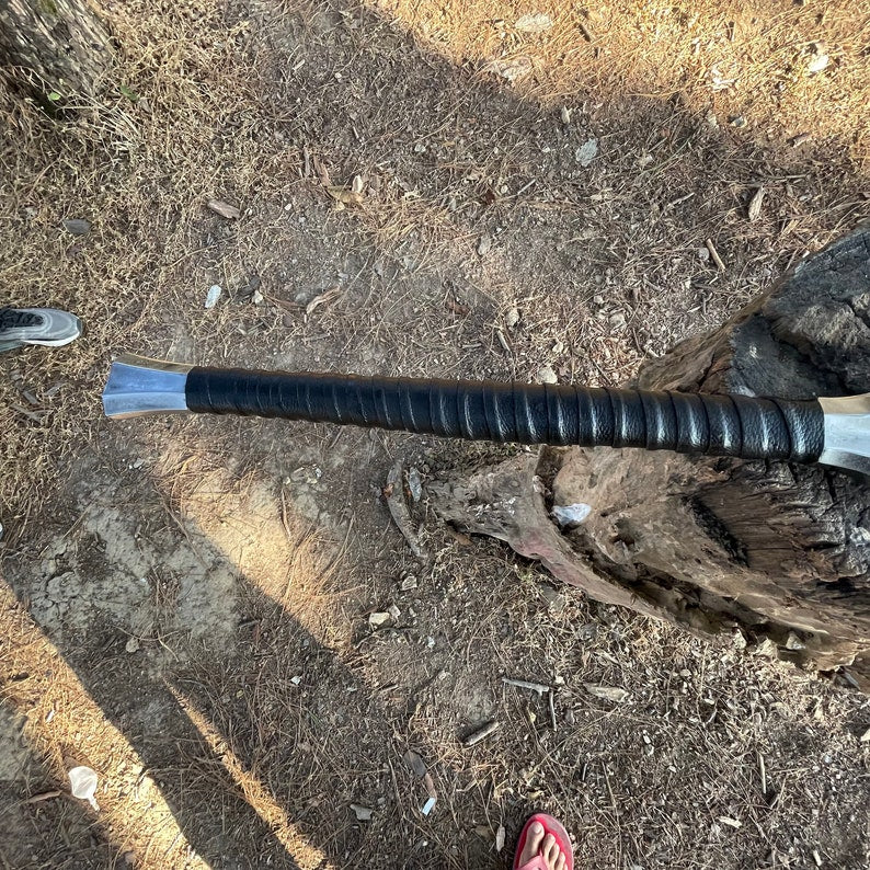 Black handled machete knife with leather strap in log close look detailed