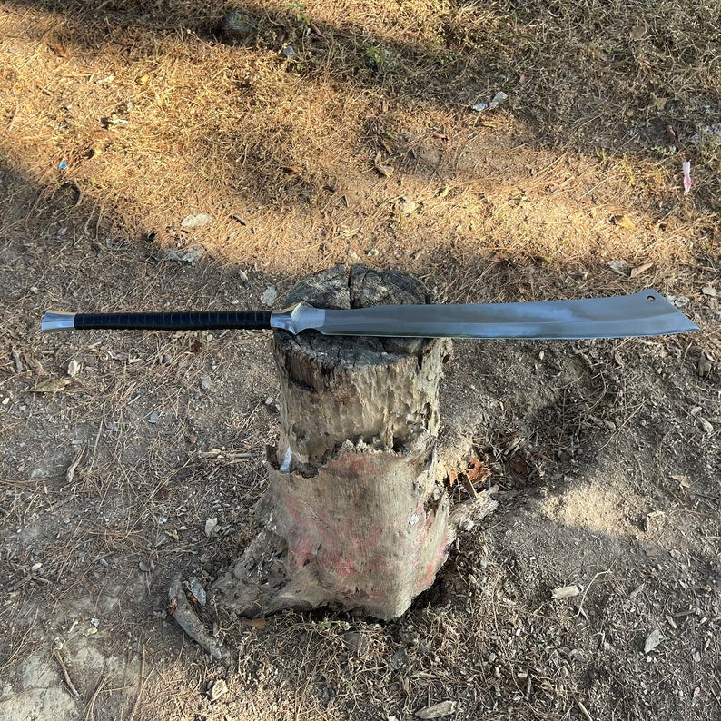 Shining long metal machete sword on a log with a natural outdoor used for camping and protection and wildlife