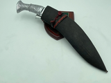 A 12 inch hand forged kukri with a polished blade and a brass handle, accompanied by a black leather scabbard. The knife is displayed on a white background.