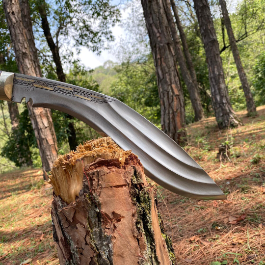 A 10 inch Farmer 3 Chirra Kukri knife with a hand-bitten Gurkha blade design, resting on a wooden stump in a natural outdoor setting with trees in the background.