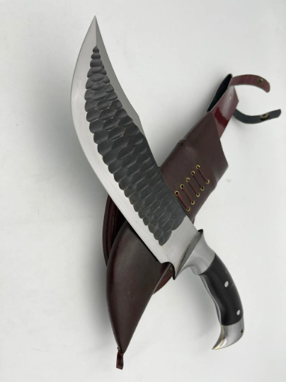 A 10 inch hand forged Bowie knife with a black and gray blade and a brown rosewood handle, displayed next to its scabbard.