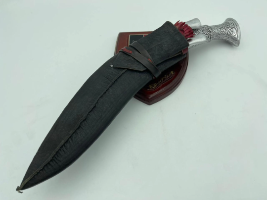 A 12 inch hand forged kukri with a polished blade and a brass handle, accompanied by a black leather scabbard.