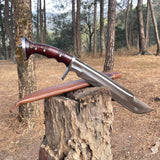 Decorative shining blade sword with wooden handle on a tree stump in a forest for camping and protection