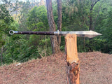 Long knife with a black handle on a wooden stump in a forest setting