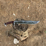 Sword with a wooden handle on a dirt ground used in forest for camping and protection