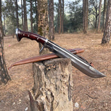 Long knife with wooden handle and leather sheath on a tree stump in a forest for camping and protection