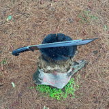 Machete Sword embedded in a tree stump on dry grass for camping and protection