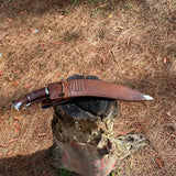 Traditional Salyani kukri with sheath on a wooden stump outdoors