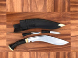 Two kukri knives with sheaths on a wooden surface with its miniature self