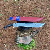 Large machete knife with a red leather sheath on a rock in a forest  for camping and protection