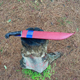 Red leather sheath with machete knife with a black handle on a tree stump in a forest for camping and protection