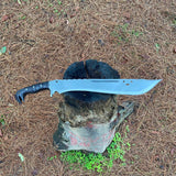 Large machete knife with a black handle and shining blade on a tree stump in a forest for camping and protection
