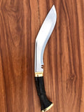 Kukri knife with a black handle and gold accent with shining blade on a wooden background