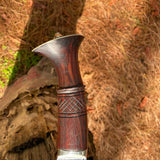 Polished wooden handle with metal tip on a natural background with decorative design