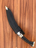 Knife with black handle and blade on a wooden surface Entire kukri with sheath laid flat for display