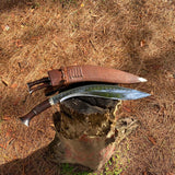 Close-up of Salyani kukri blade curve and polished finish with brown leather sheath beside