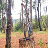 Two traditional knives on a wooden stump in a forest setting
