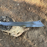 Metal machete blade on a rocky and dry surface with clear shine on blade 