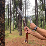 Two knives held by a person in a forest setting