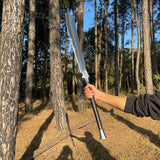 Person holding a large sword in a forest used for camping and protection form wildlife