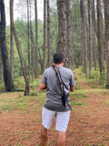 Man walking through a forest with a khukuri knife set over his shoulder