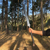 Person holding a large sword in a forest setting