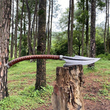 Decorative axe with a curved blade and wooden handle on a tree stump in a forest setting.