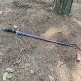 Sword lying on dry grass with a tree stump in the background