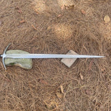Sword lying on dry grass with stones in the background