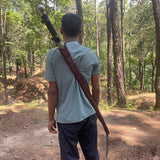 Person carrying a sword in a forest setting 