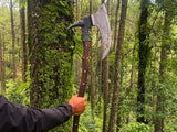 Person holding a large axe in a forest setting